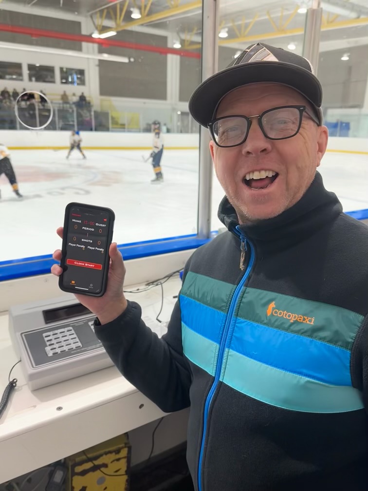 Smiling hockey dad holding up Blitz app